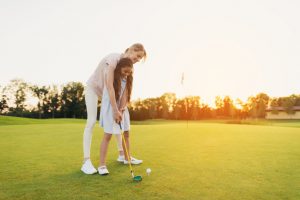 mother teaching daughter golf