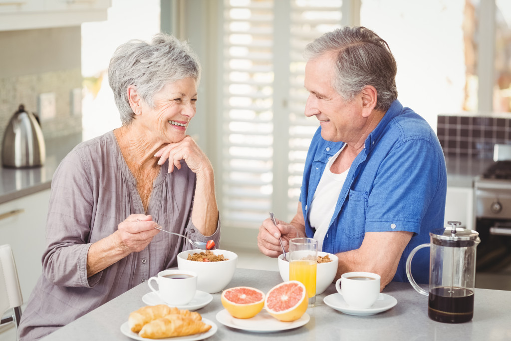 A senior man and a senior woman enjoying oats, coffee, and fruits for breakfast