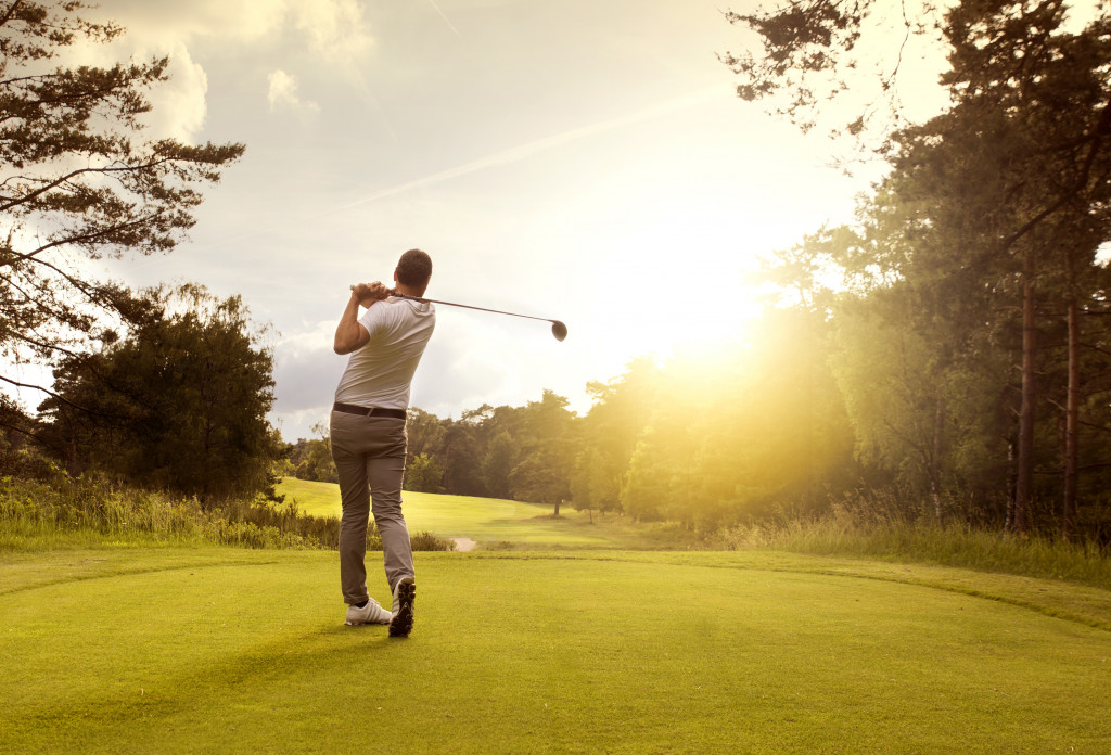 man playing golf on golf course on sunrise or sunset