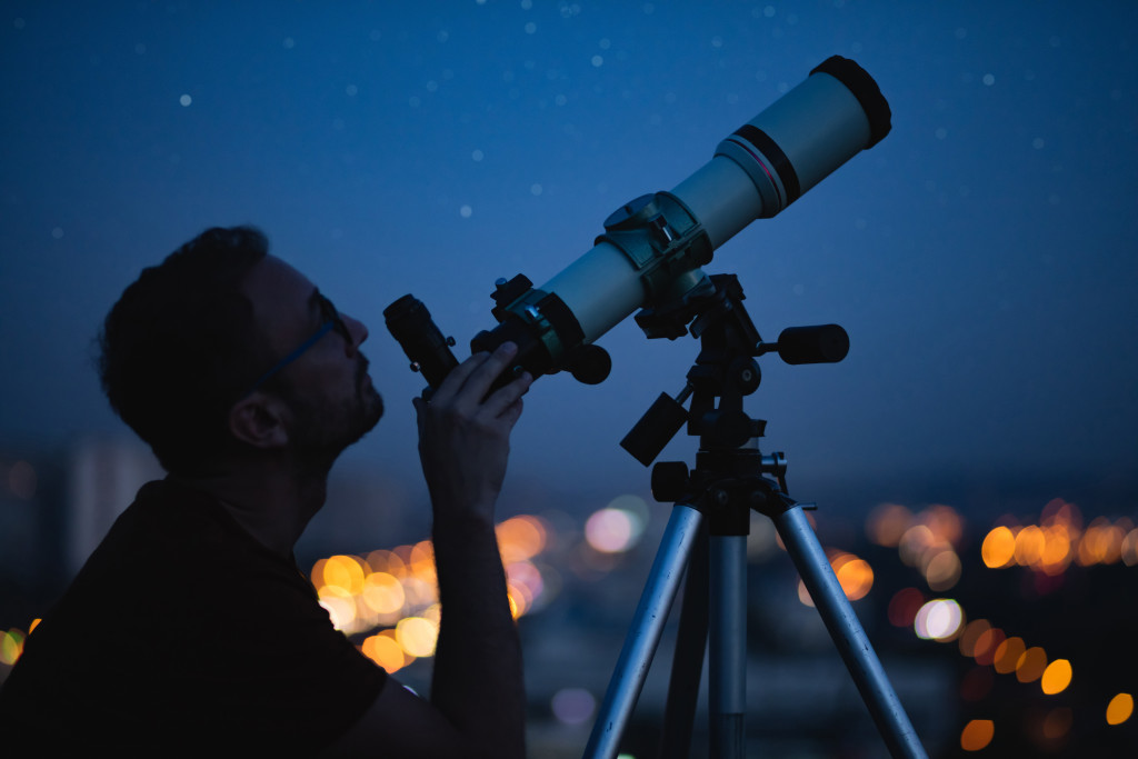 A man looking at the sky using a telescope